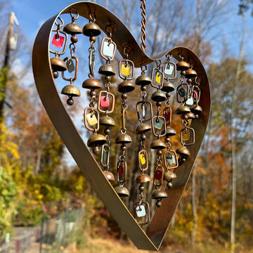 Rustic copper heart-shaped wind chime with hanging brass bells and colorful enamel square charms on metal chains
