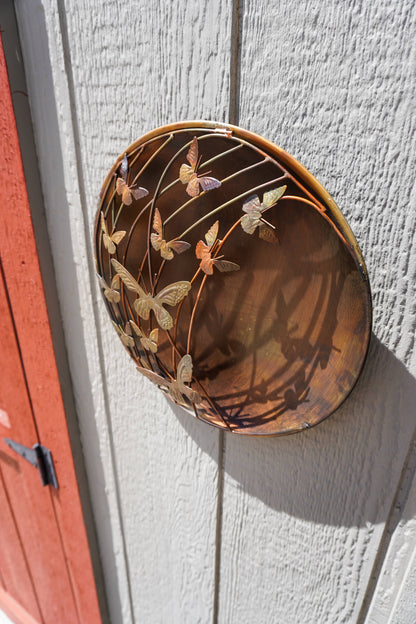 Decorative metal wall art with butterfly design on a light gray wall.