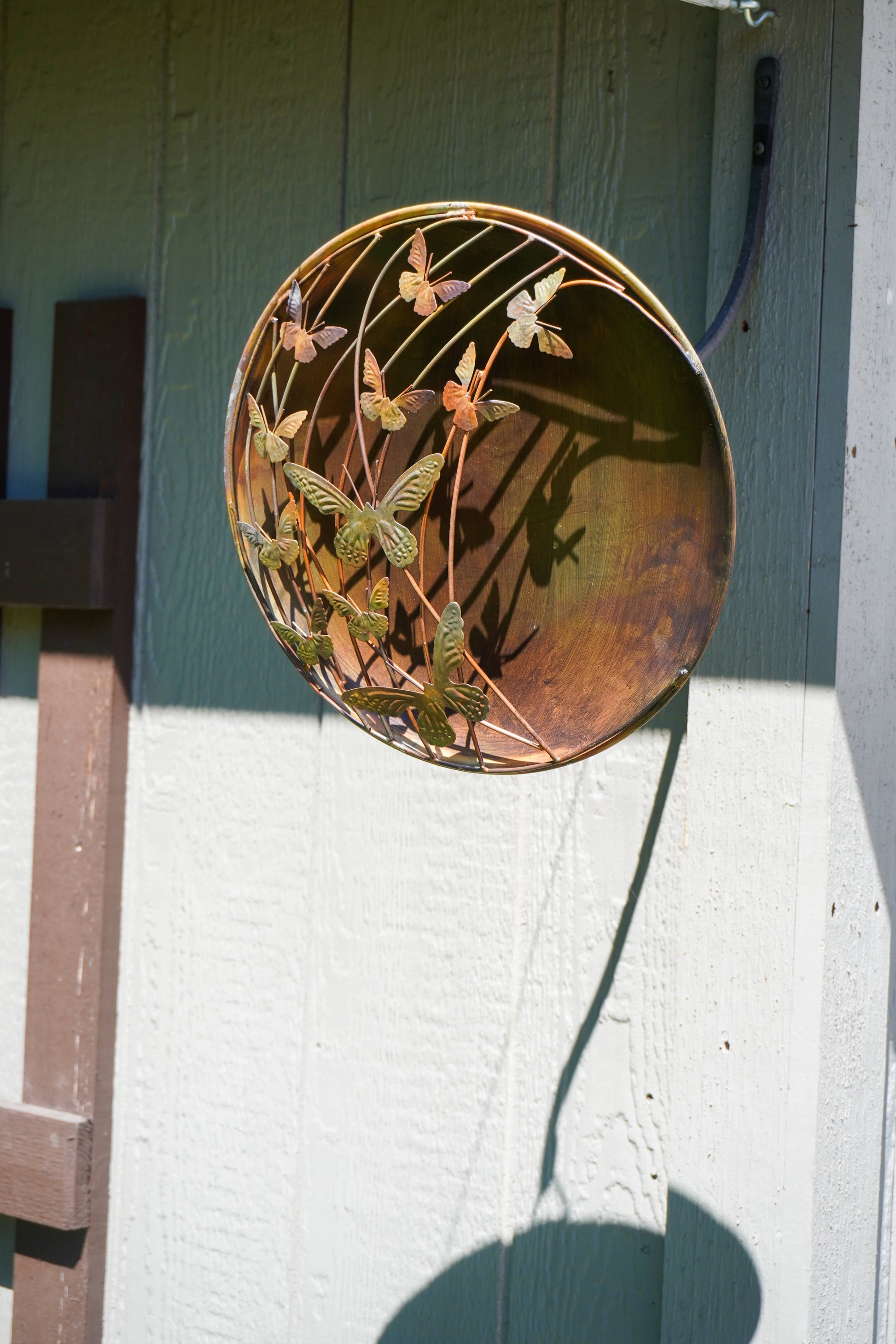Decorative circular metal plate with butterfly design on a wall