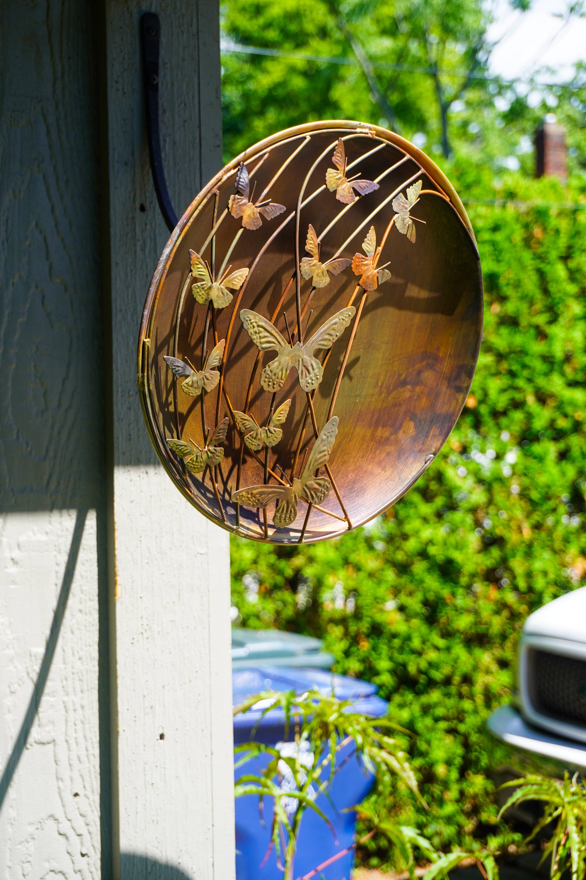 Decorative metal plate with butterfly design attached to a wall outdoors