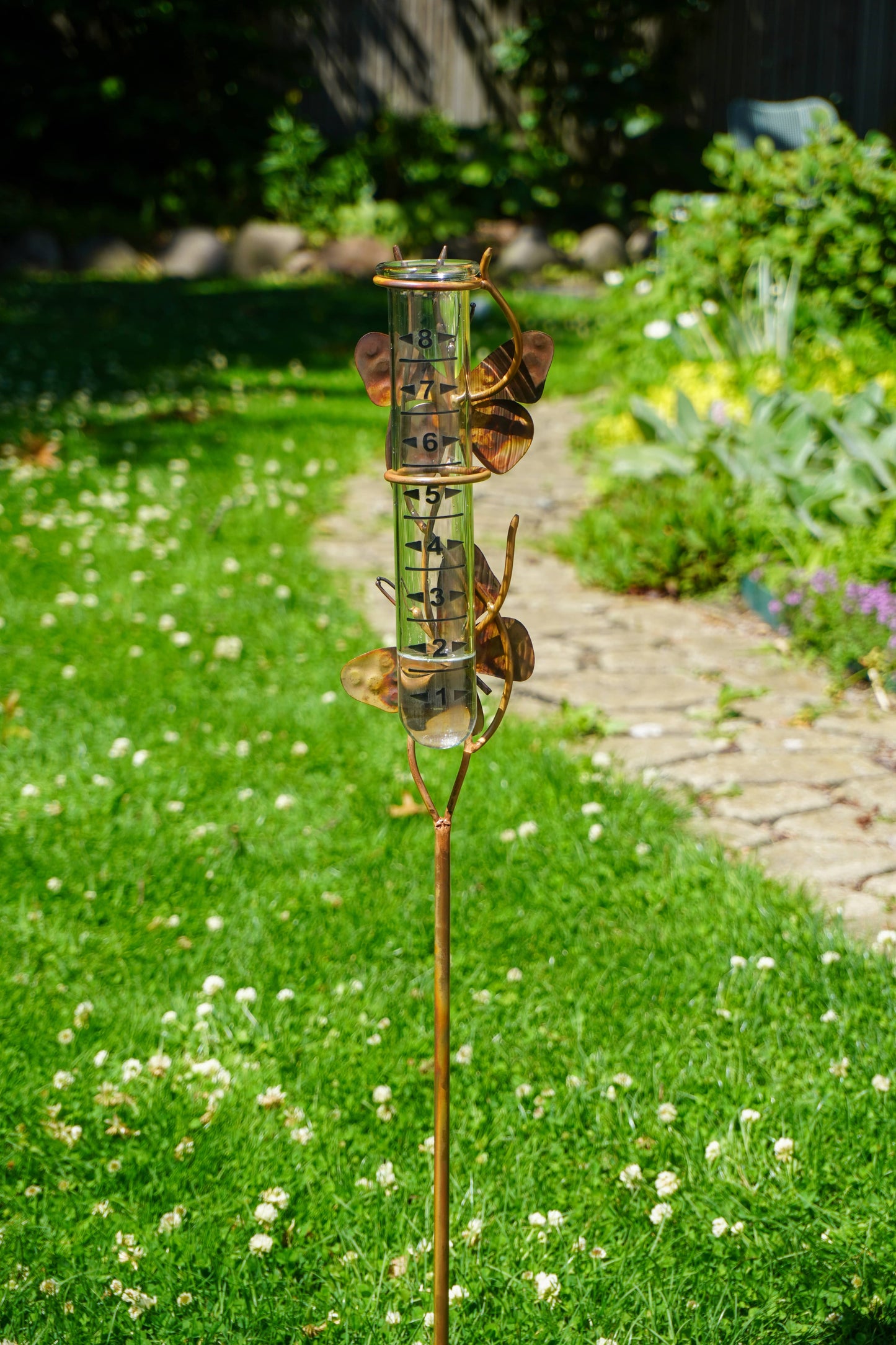 Rain gauge on a grassy lawn with a garden background