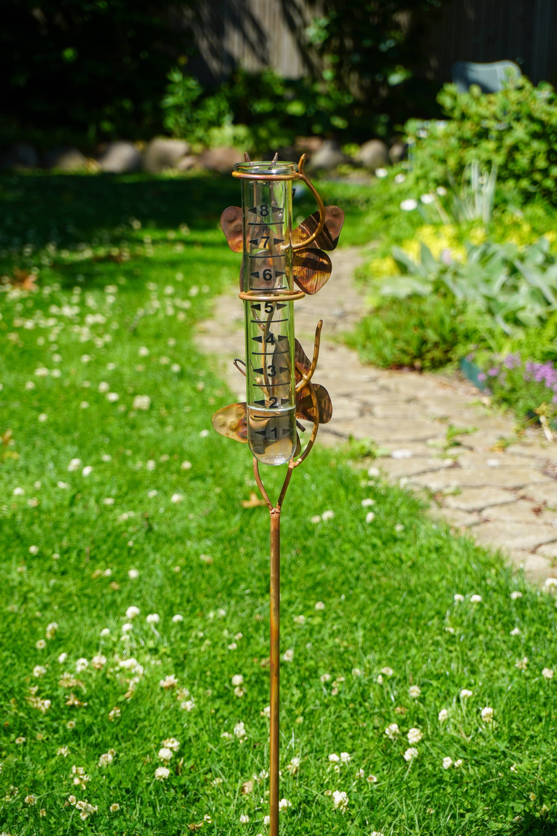 Rain gauge on a grassy lawn with a garden background