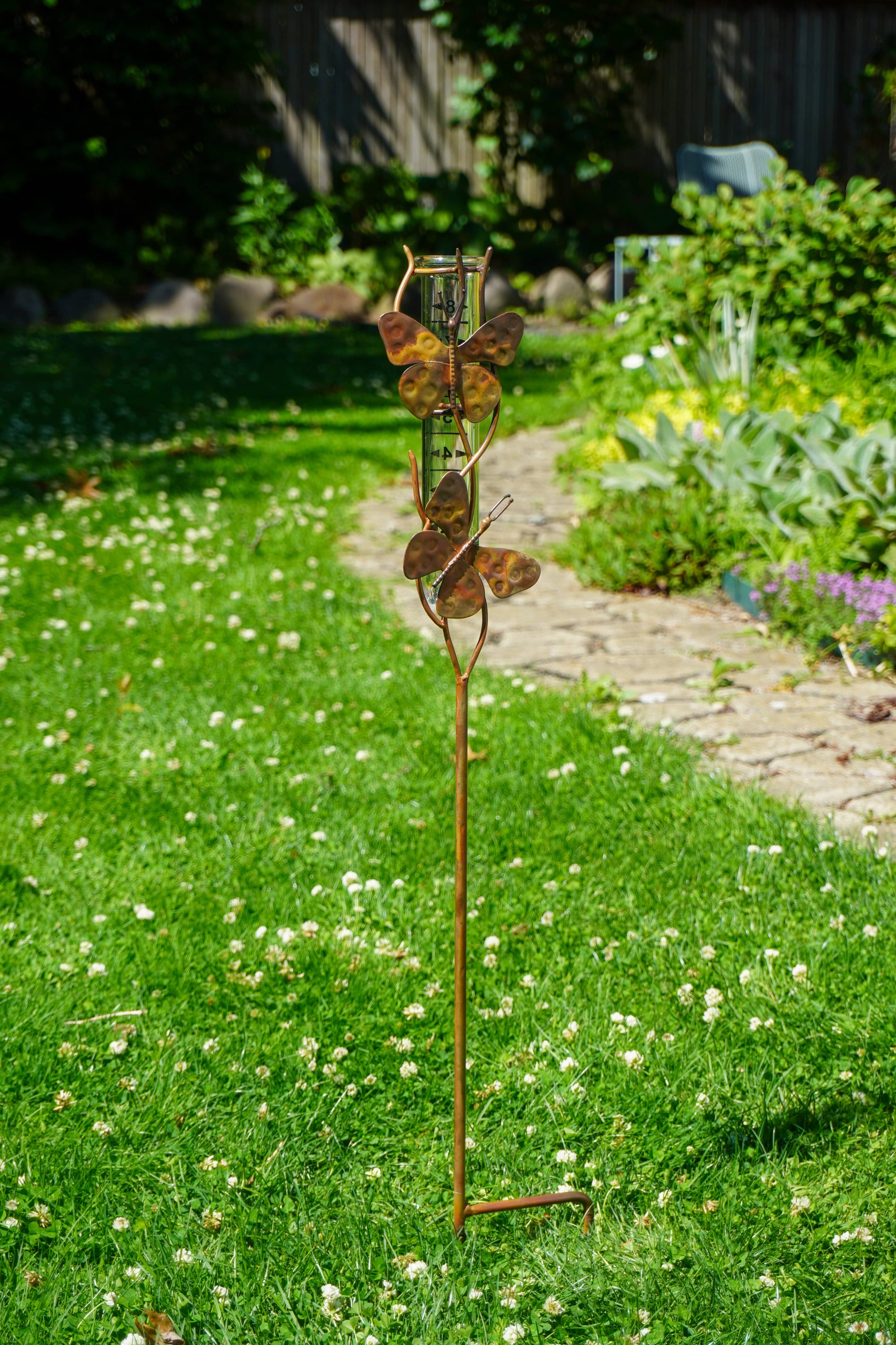 Decorative metal garden stake with butterfly design on a grassy lawn