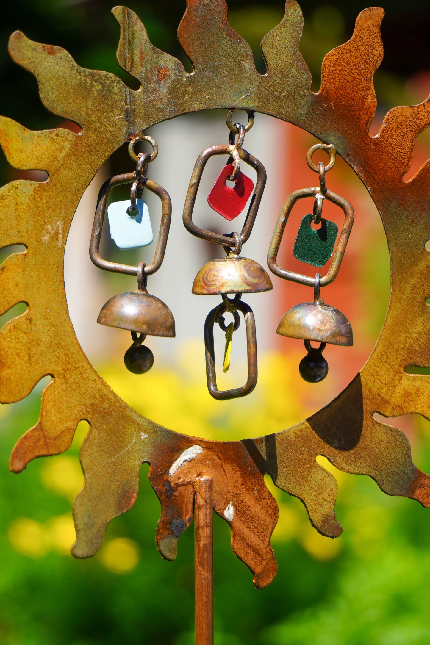 Decorative metal sun with hanging bells against a blurred natural background
