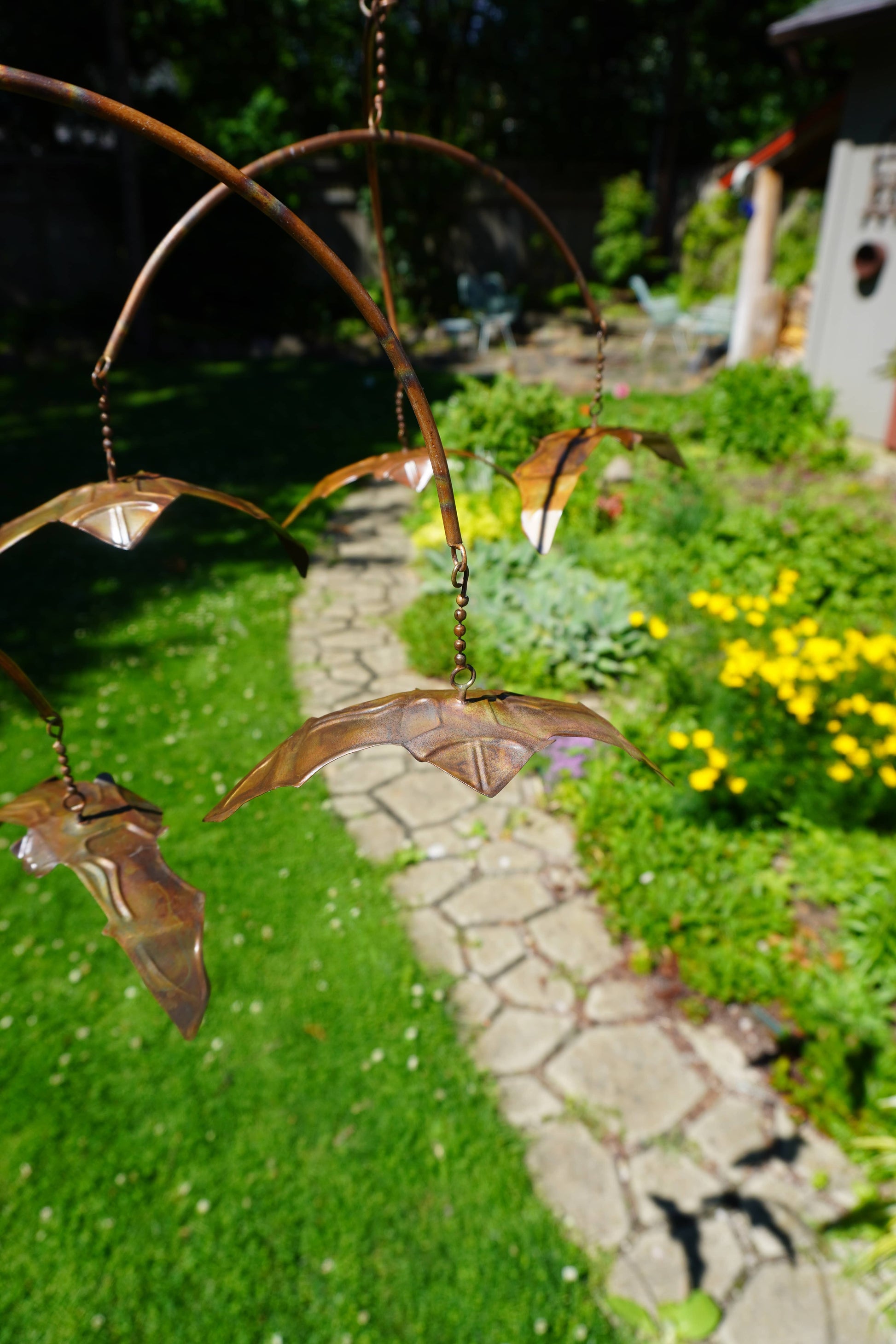 Rustic metal hanging mobile with layered arched arms and small copper-toned bat figurines suspended by chains