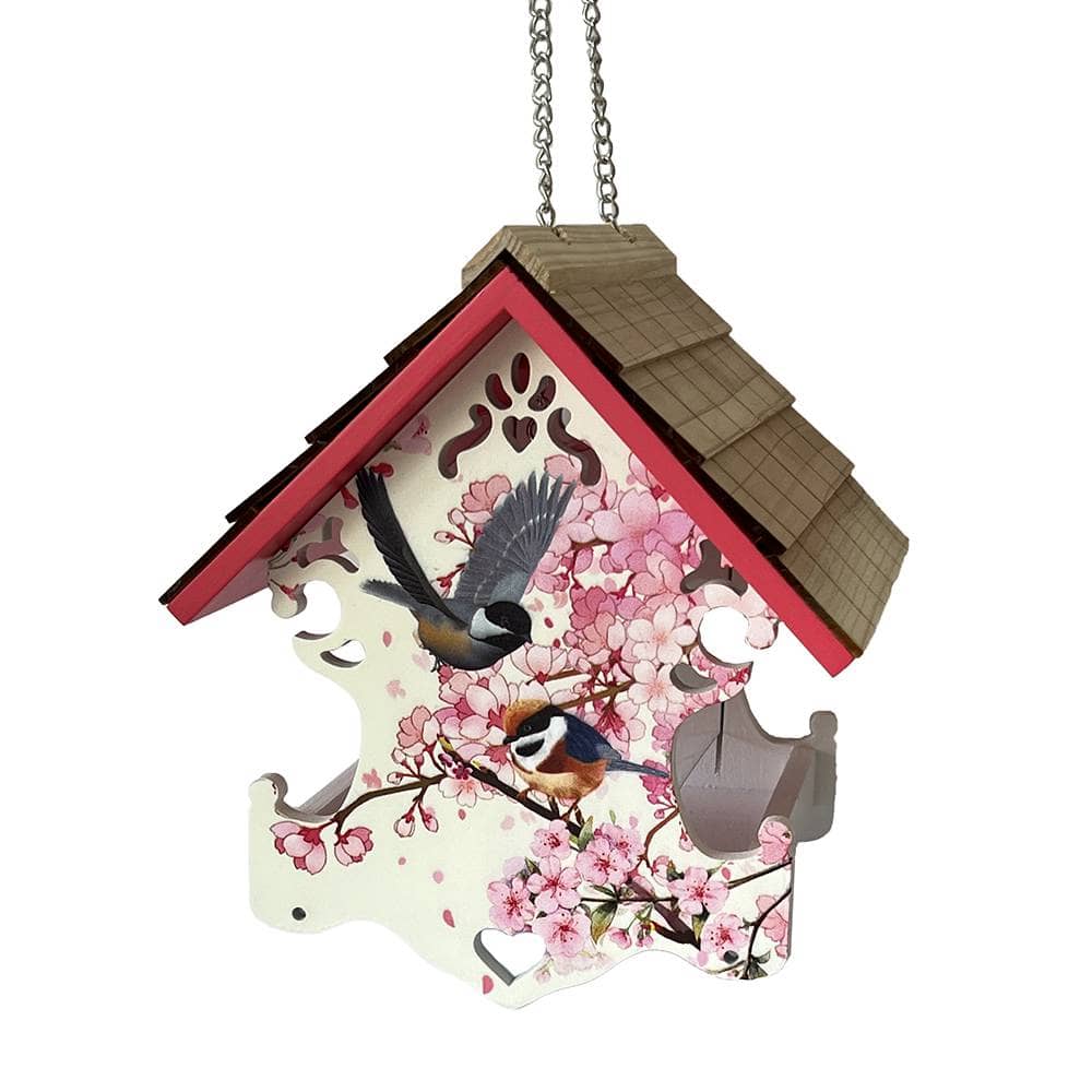 A hanging birdhouse-shaped decorative feeder with a pink cherry blossom print, two birds, and a brown shingled roof, shown on a plain white background.