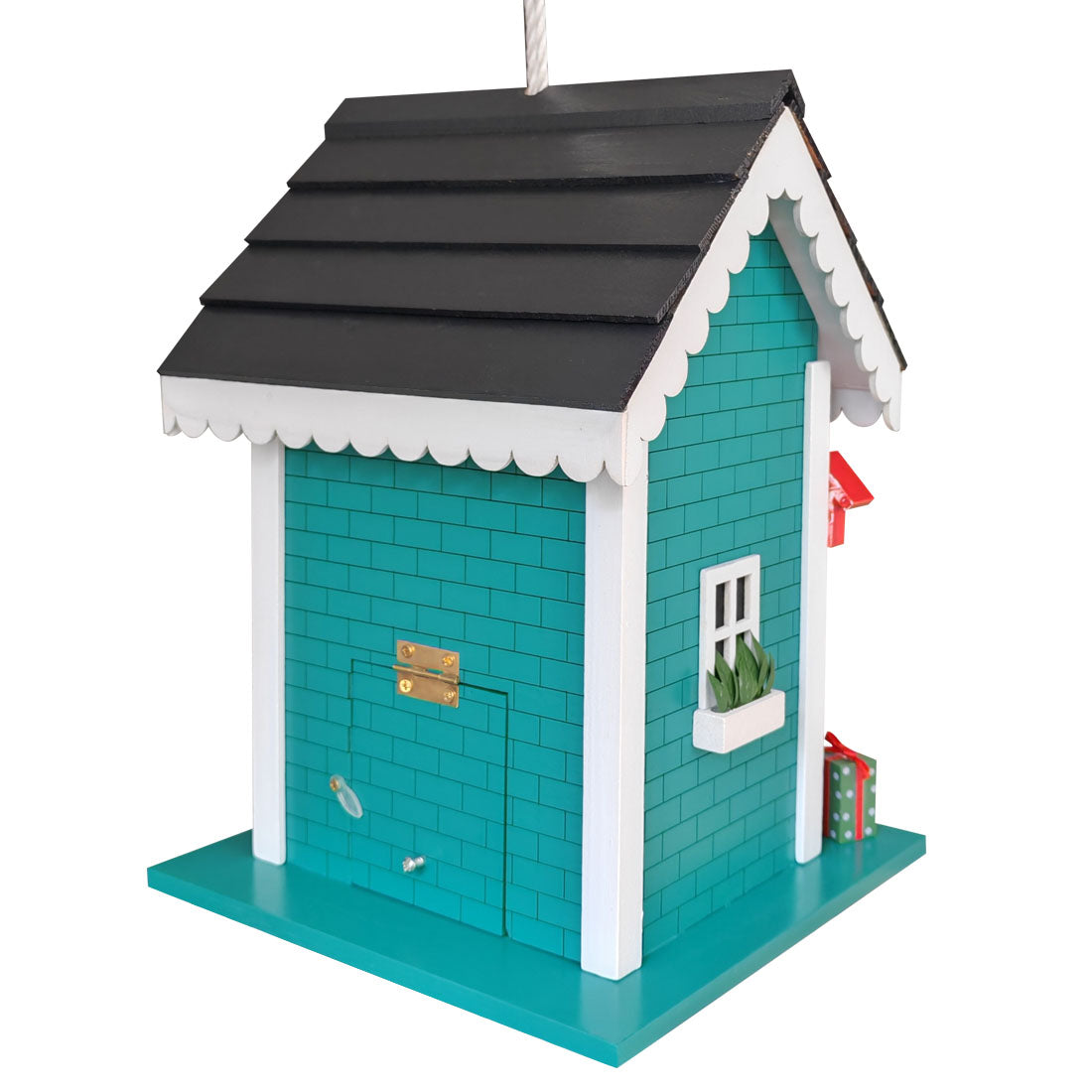A decorative birdhouse shaped like a small house with turquoise walls, a black shingled roof, white trim, a small window with a plant, and a red flag, shown on a plain white background.