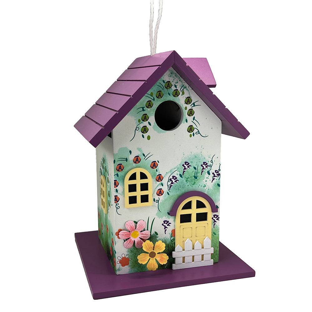 A decorative birdhouse with a purple roof and base, decorated with painted flowers, ladybugs, birds, and vines on a white front panel, shown against a plain white background.