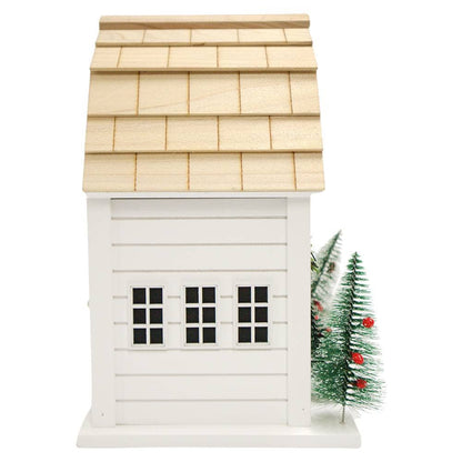 A small white wooden house-shaped ornament or decorative structure with a natural wood shingled roof, three black window panes, and a small decorated green Christmas tree beside it on a white background.