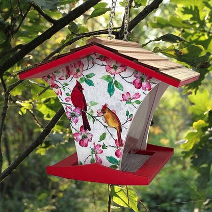 Bird feeder with floral design and red border hanging in a tree