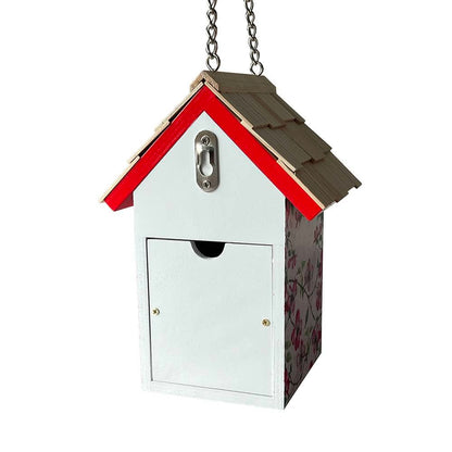 A hanging birdhouse-style mailbox with a white front door, red roof trim, brown shingled roof, and floral-patterned side panel, shown on a plain white background.