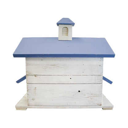 A rustic wooden birdhouse painted white with a blue roof and small blue chimney detail, isolated on a white background.
