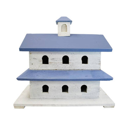 A rustic wooden birdhouse designed like a small church or chapel, featuring a white distressed wood body with blue painted roofs and a small matching blue cupola on top, set against a plain white background.