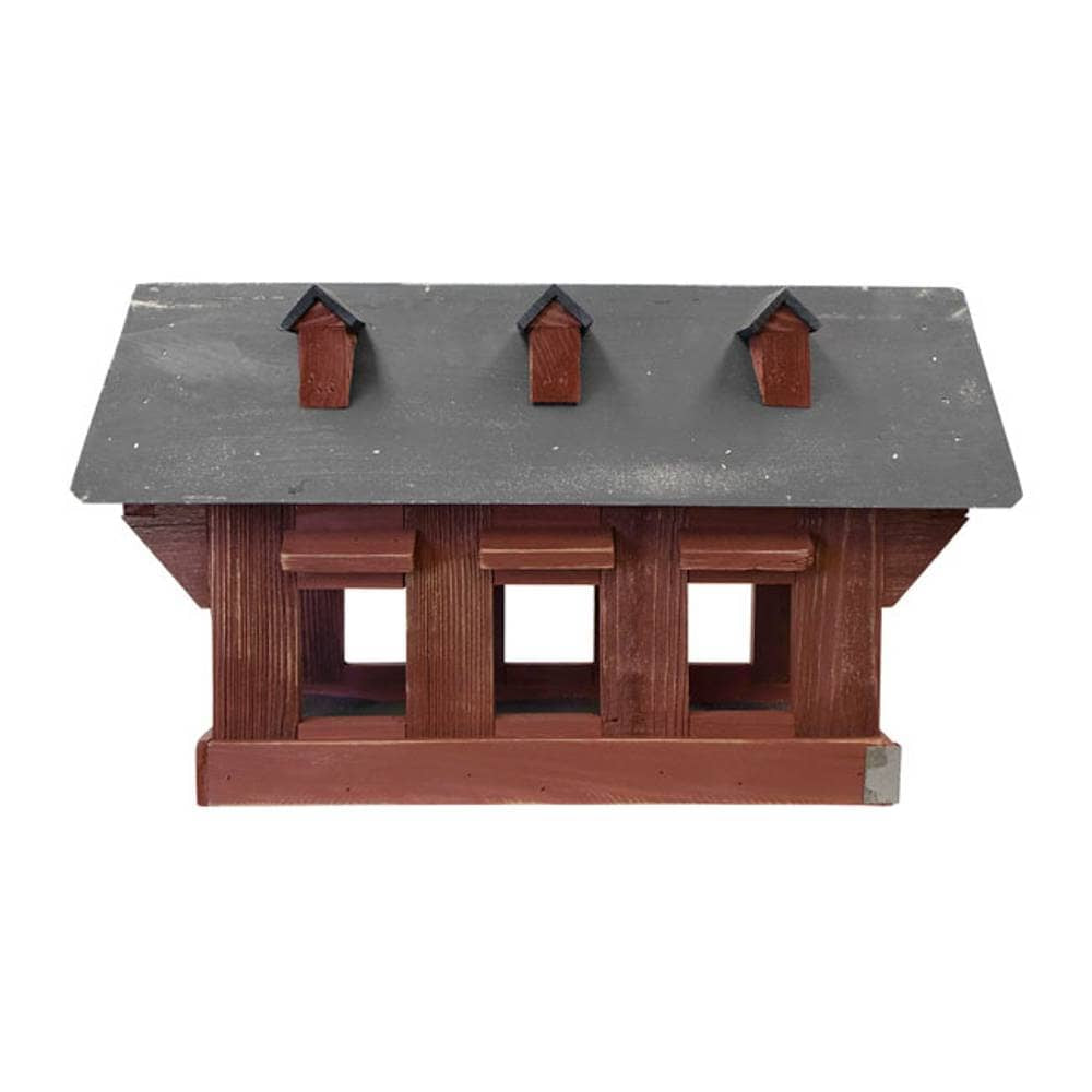 A wooden model birdhouse with a dark gray slate-textured roof, three small chimney stacks, and three window openings on a plain white background.
