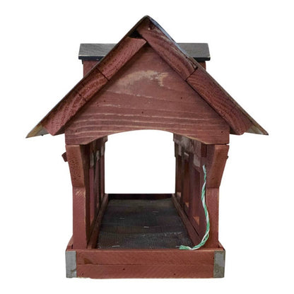 A wooden birdhouse with a reddish-brown painted finish, a dark gray roof, and a green wire hanging from the side, shown against a plain white background.