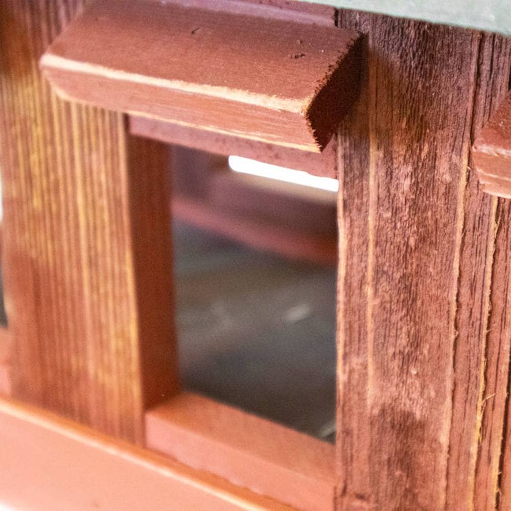 Close-up detail of a reddish-brown wooden structure with a rectangular opening and visible wood grain texture.