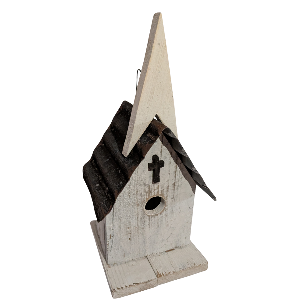 A rustic church-shaped birdhouse with a distressed white painted wood body, a dark brown corrugated metal roof, and a small black cross on the front.