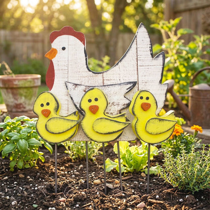 A rustic metal garden stake set featuring a large white chicken silhouette with a red comb and three small yellow chicks with orange beaks, displayed in a garden bed.