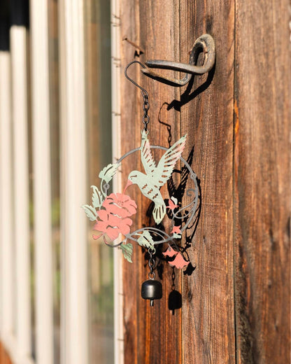 Metal wind chime ornament featuring a hummingbird and pink flowers in mint and coral tones with a small black bell