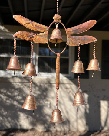 Rustic copper-toned metal dragonfly wind chime with eight small hanging bells on chains